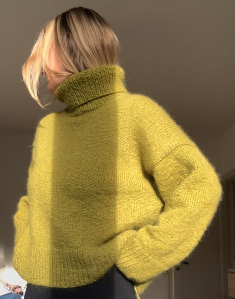 Kvinde i olivengrøn Sweater No. 25 med rullekrave set forfra